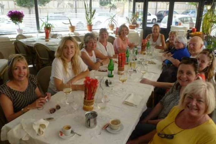 Painting holiday guests sitting around a dinner table in Sicilian restaurant