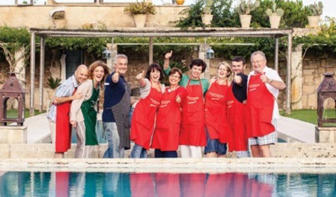 group of guests wearing aprons and laughing in front of the swimming pool