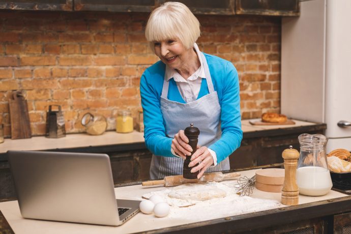 Woman taking part in online cooking class with laptop in her kitchen