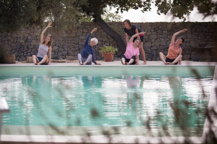 Pilates group stretching by the pool in Sicily